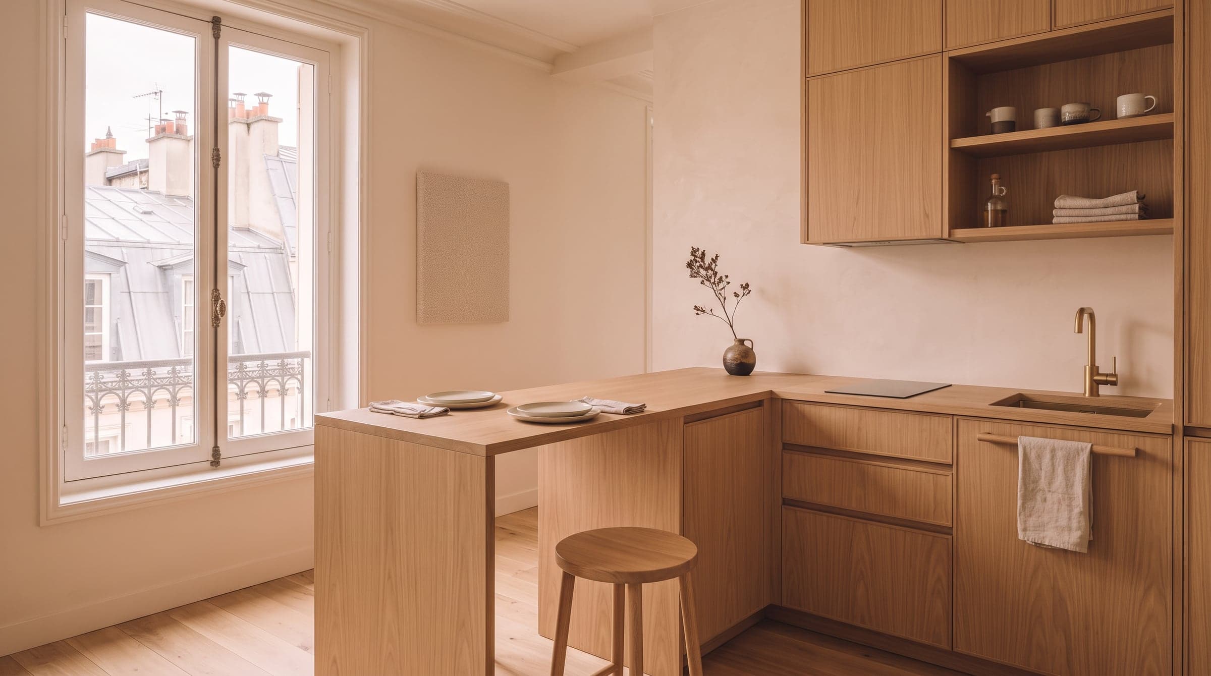 An oak peninsula worktop attached to a run of kitchen cabinets, its far end opening onto a small dining corner